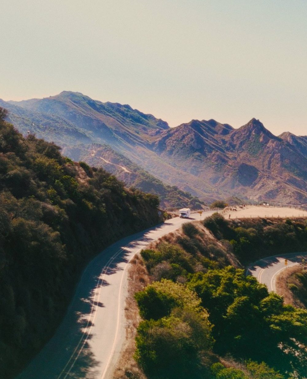 An RV winds along a mountain highway toward the border