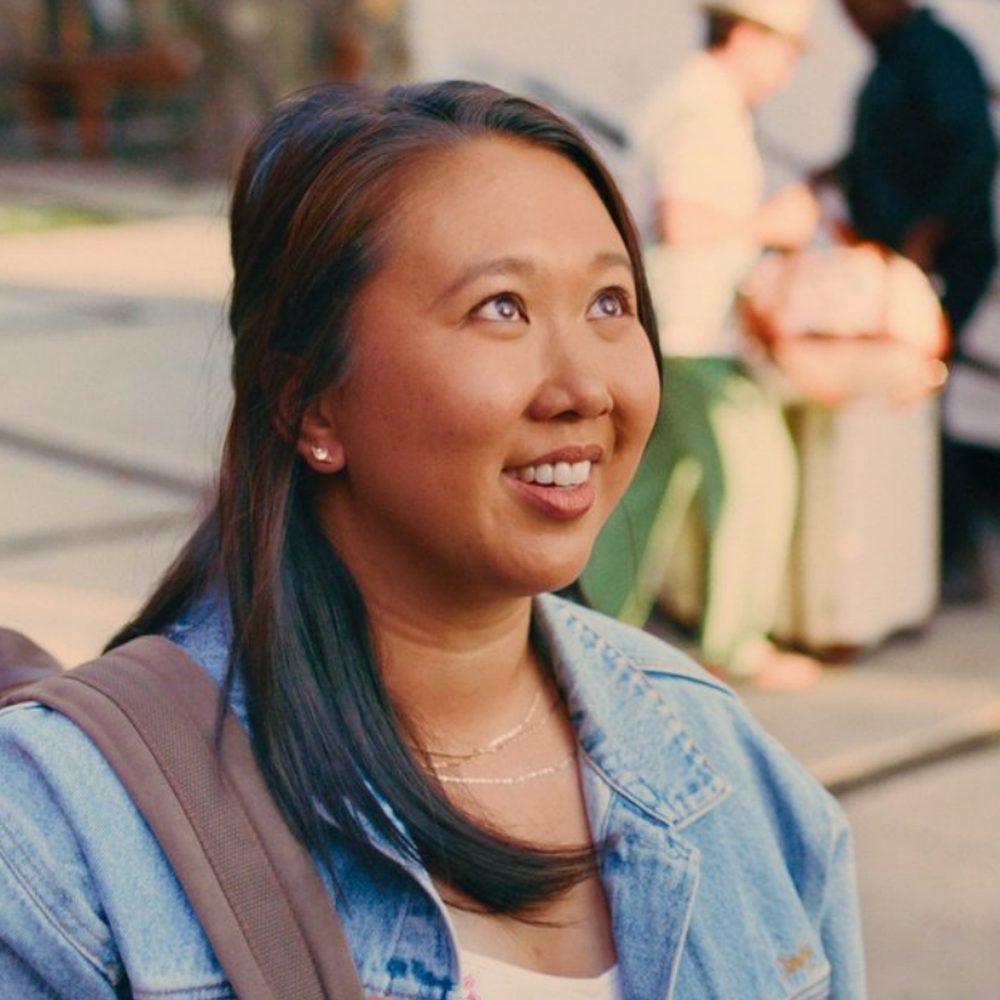 Zoey smiles up at someone with a backpack on